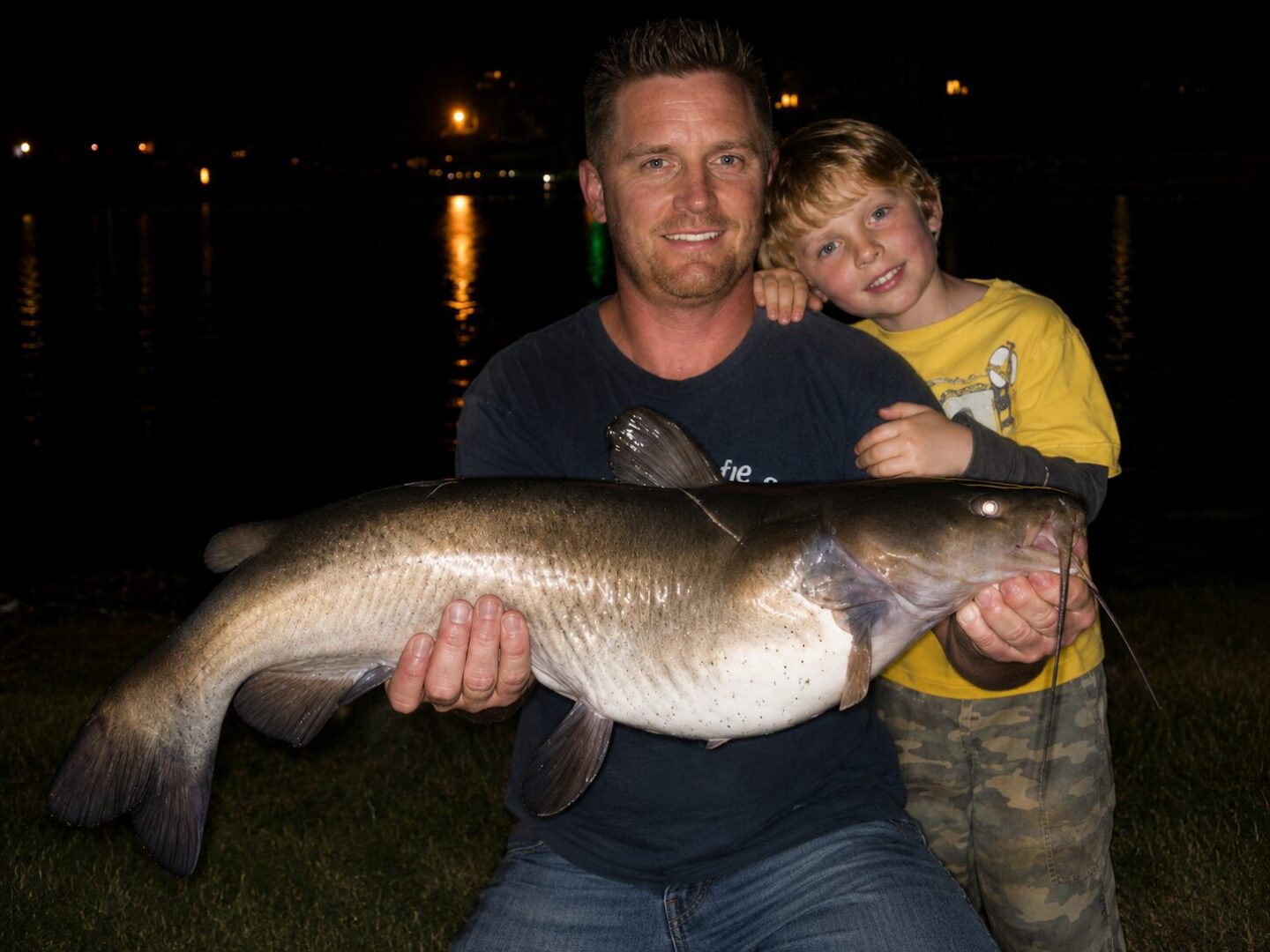 Man and child with large fish at night.