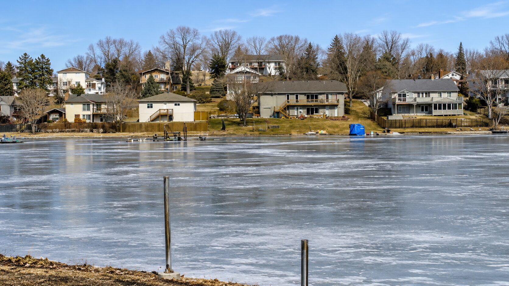 Frozen lake with houses in the background.