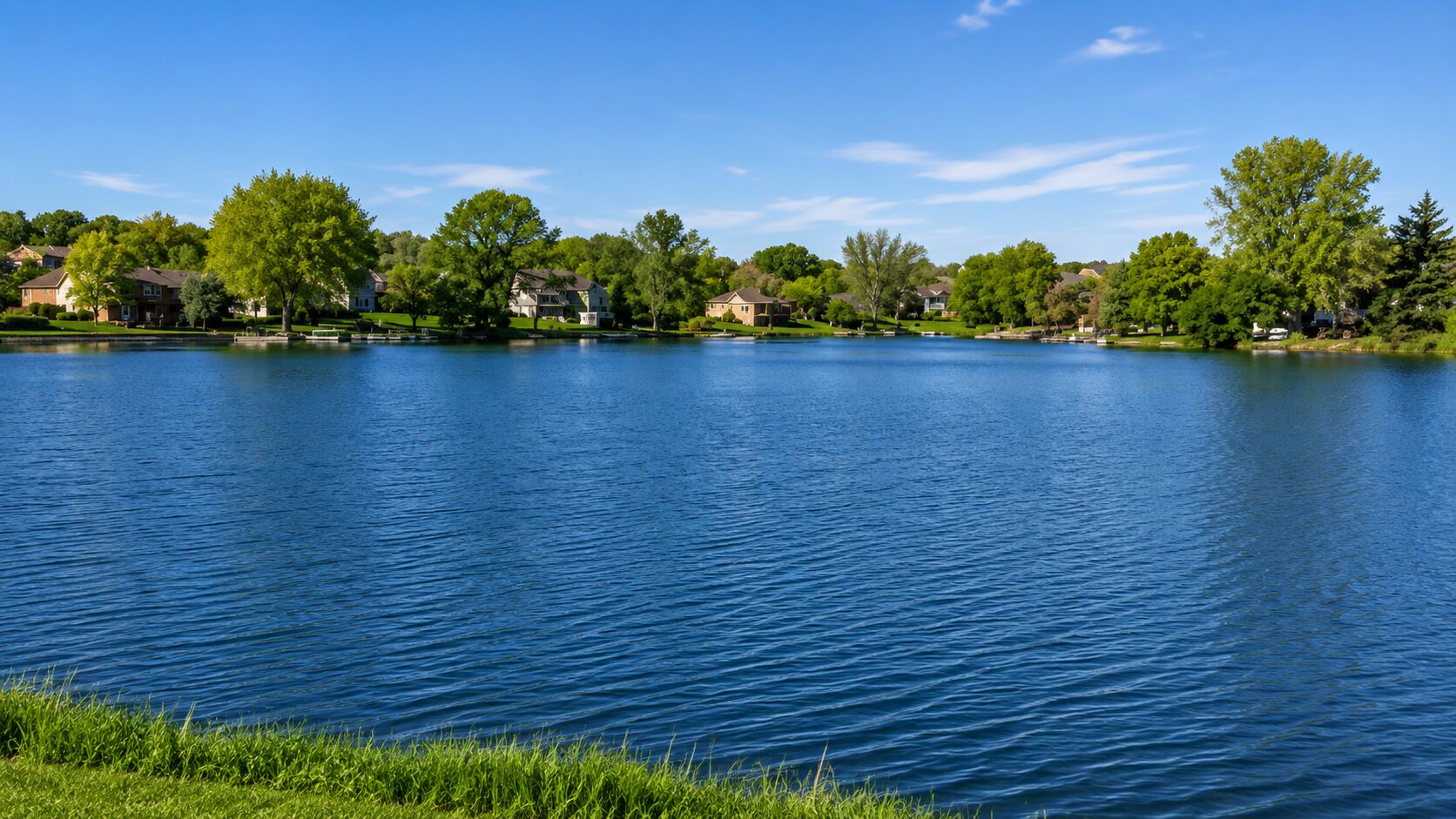 Peaceful lake surrounded by trees and houses.
