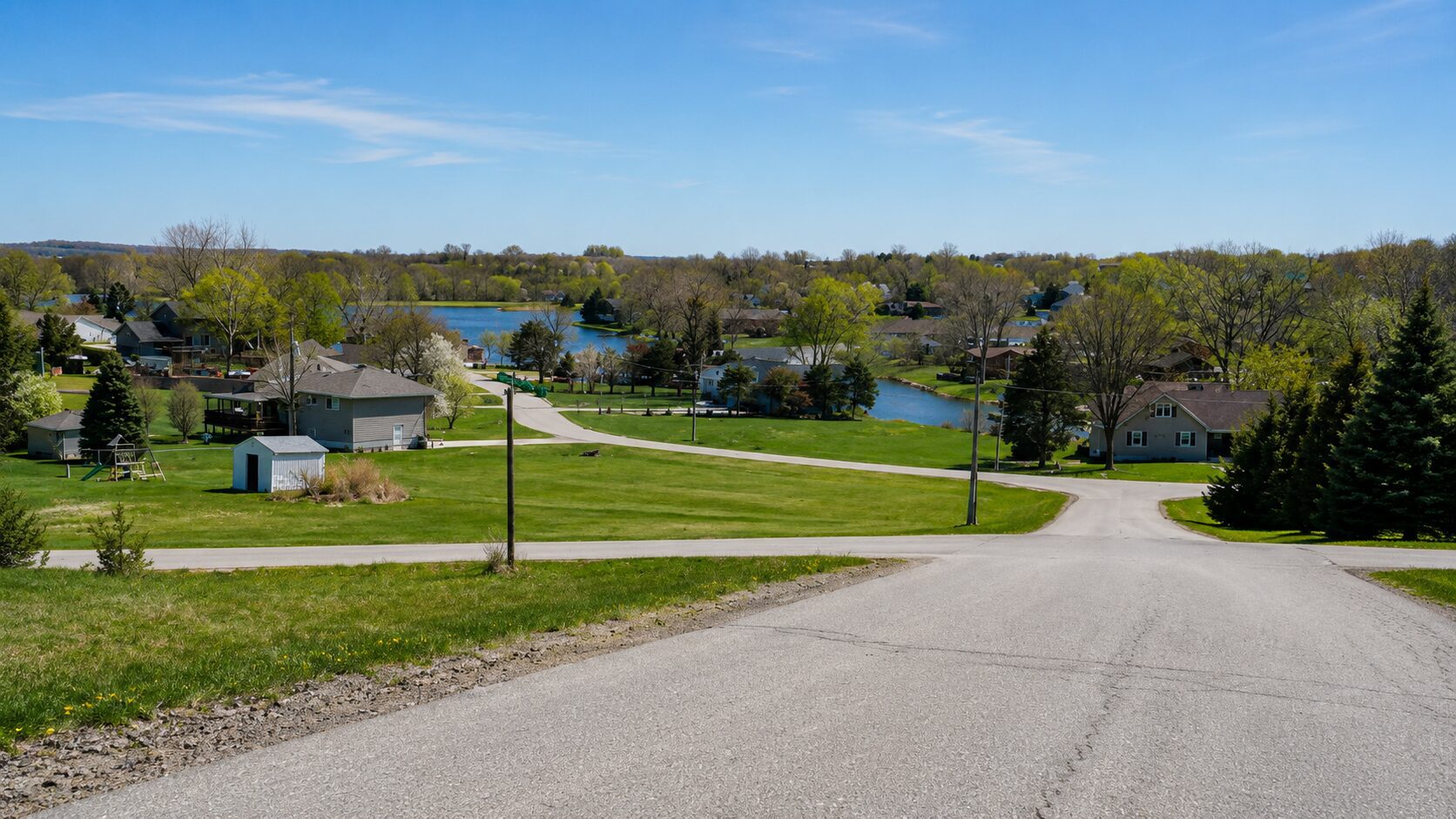 Suburban landscape with houses and a lake.
