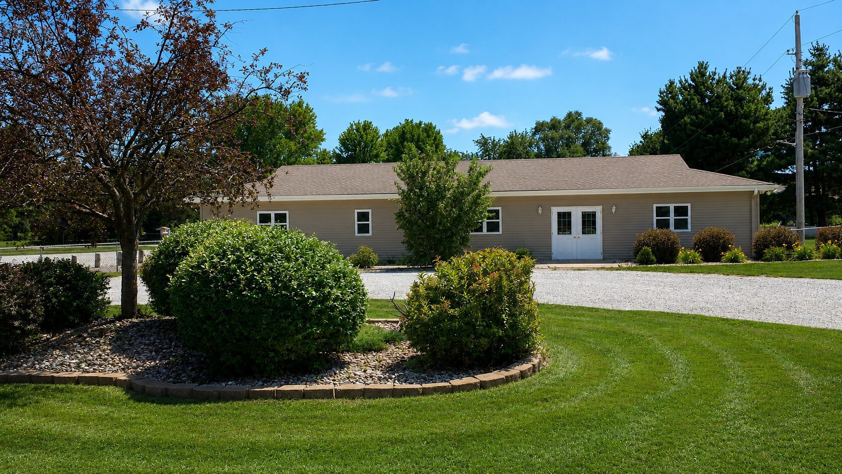 Single-story house with surrounding greenery and lawn.