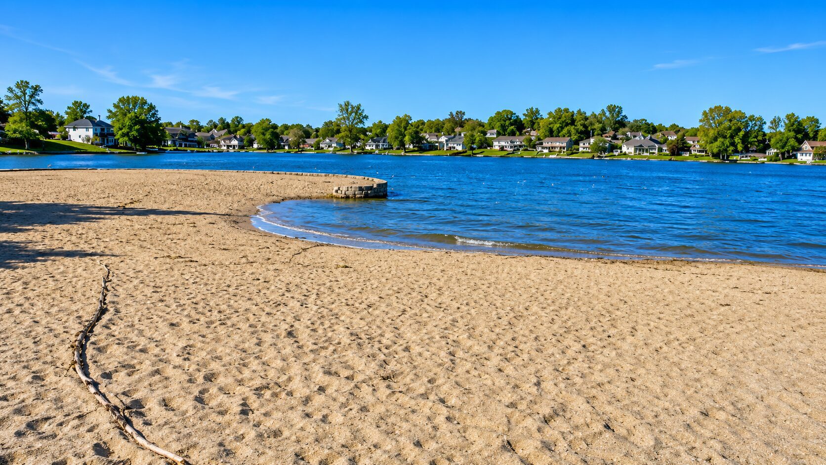Sandy beach by a calm blue lake.