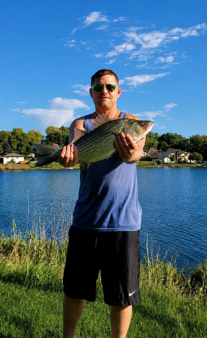 Man holding fish by a lake.