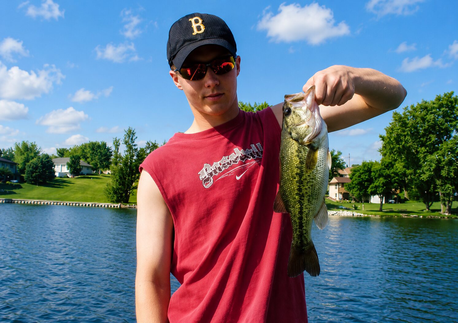 Person holding fish by a lake.