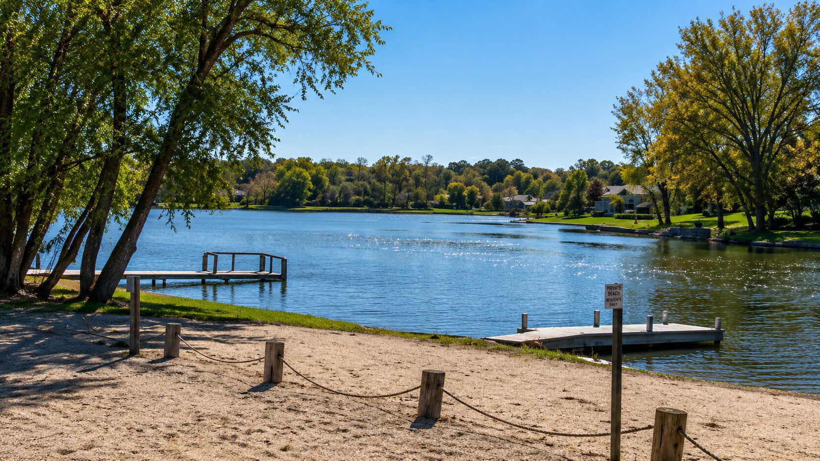 Lake with docks and trees under blue sky.